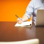 Jonge ondernemer aan bureau met laptop en notitieblok