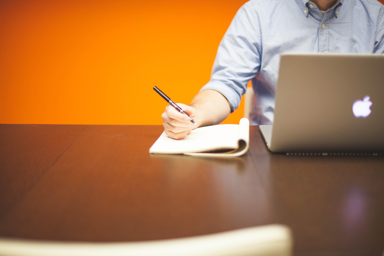 Jonge ondernemer aan bureau met laptop en notitieblok