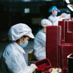Werknemer in een automotive toeleveringsfabriek bij machineonderdelen