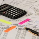 Starter aan bureau rekent met calculator en papieren voor belastingaangifte