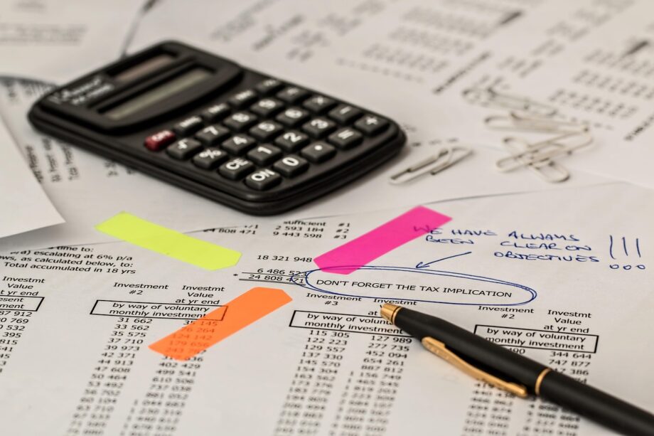 Starter aan bureau rekent met calculator en papieren voor belastingaangifte