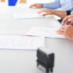 Ondernemer en medewerker bespreken en ondertekenen beleidsdocumenten aan een vergadertafel