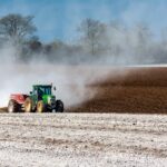 Boer op een tractor rijdt over een agrarisch perceel