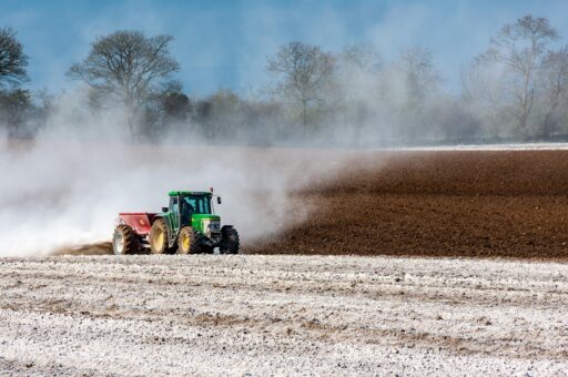 Boer op een tractor rijdt over een agrarisch perceel